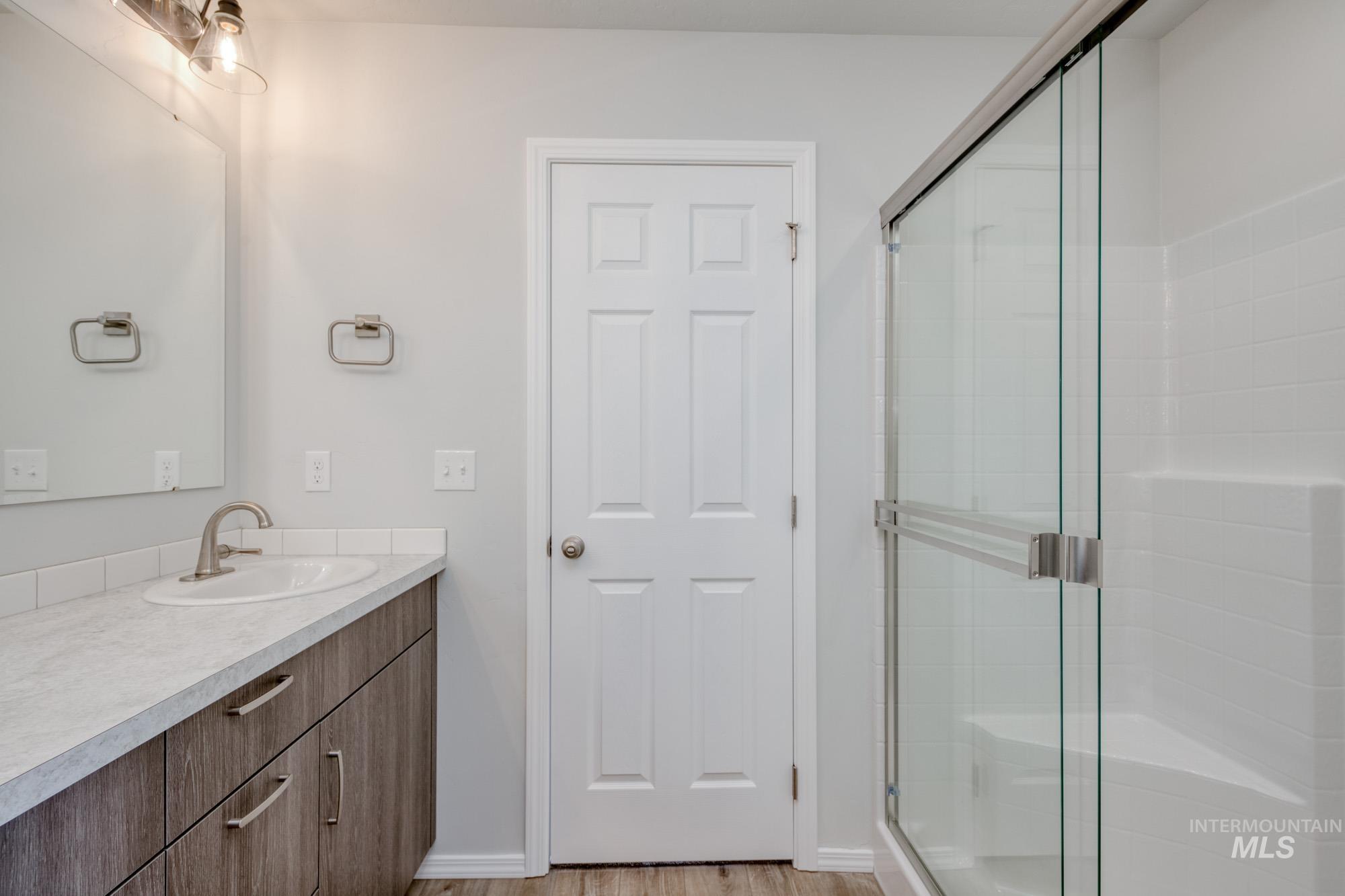 Full bath with vanity, a stall shower, and light wood-type flooring