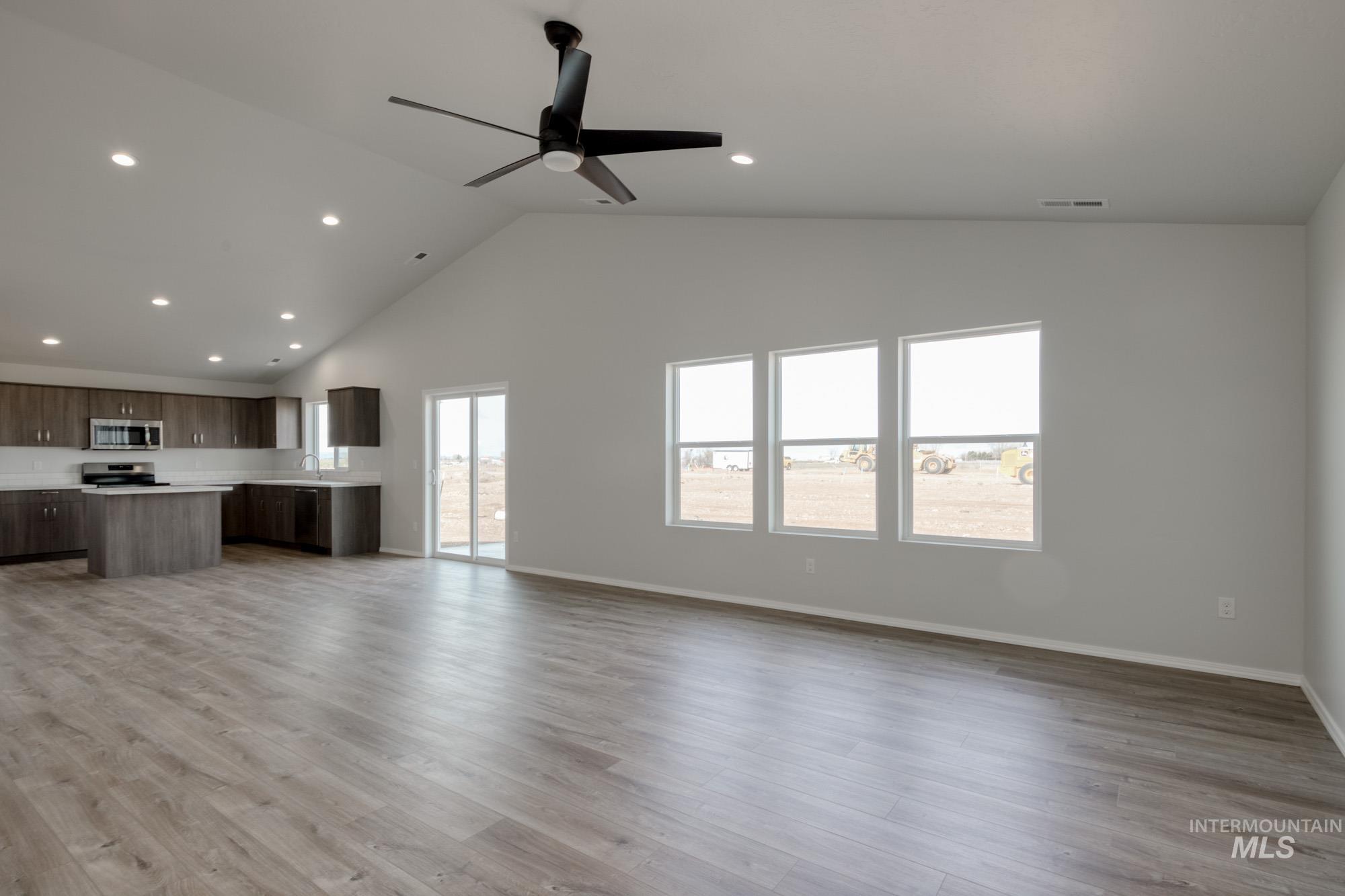 Unfurnished living room with recessed lighting, light wood-type flooring, a ceiling fan, and high vaulted ceiling