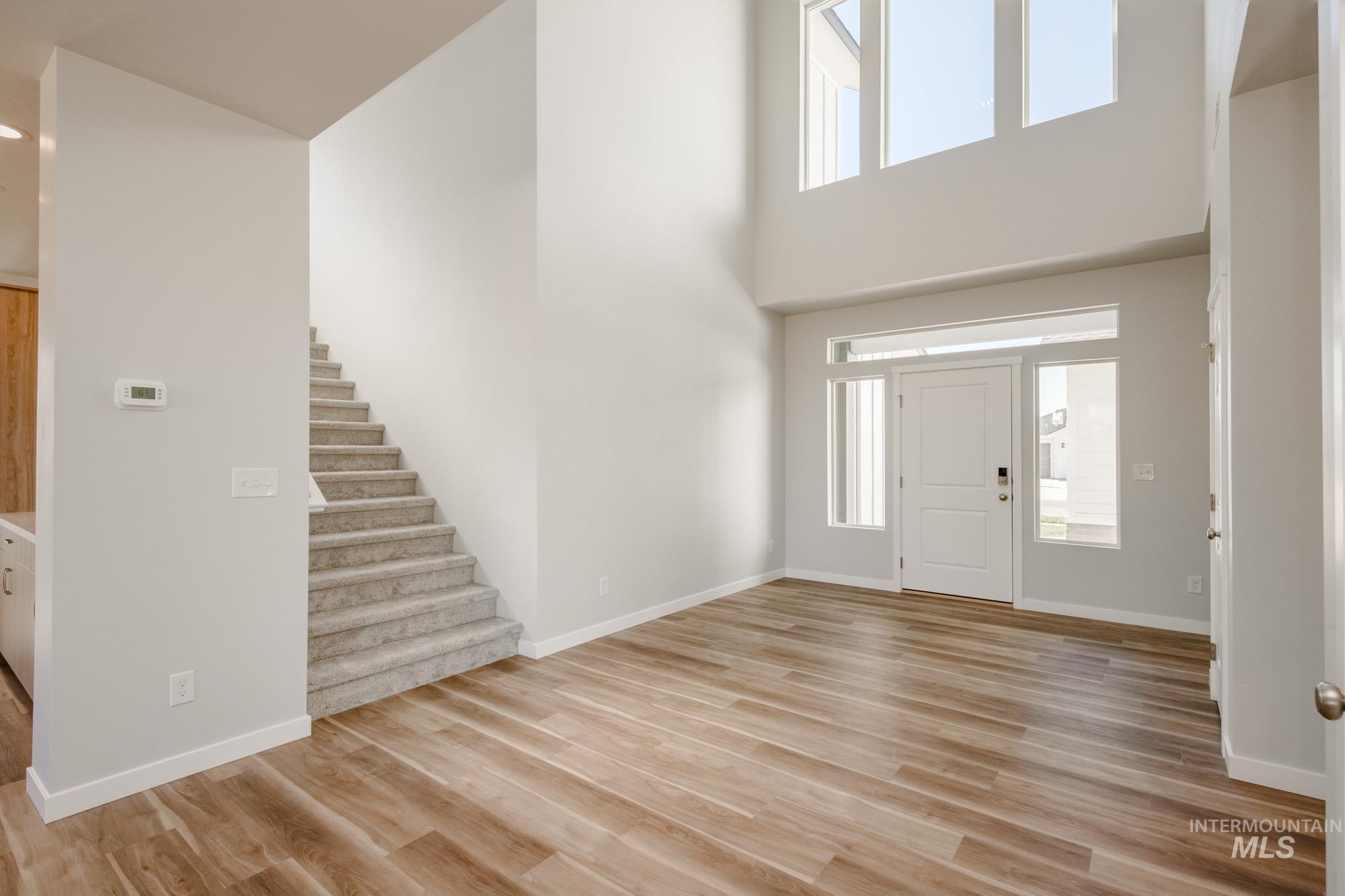 Foyer entrance featuring light wood-style flooring, stairway, and a high ceiling