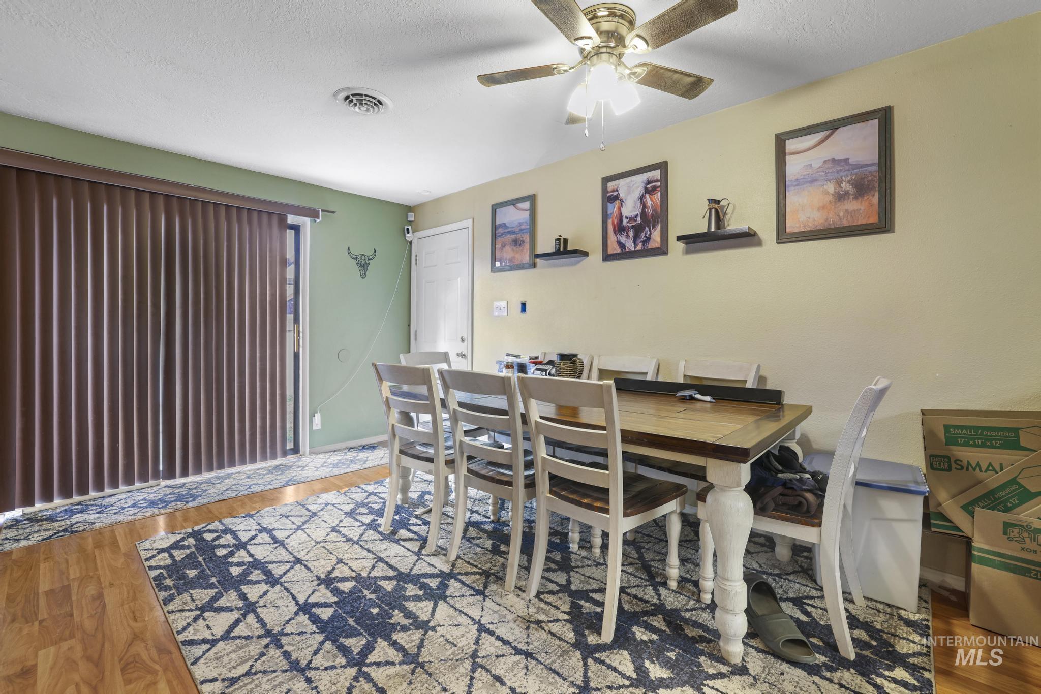 Dining area featuring light wood-style floors, a textured ceiling, and a ceiling fan