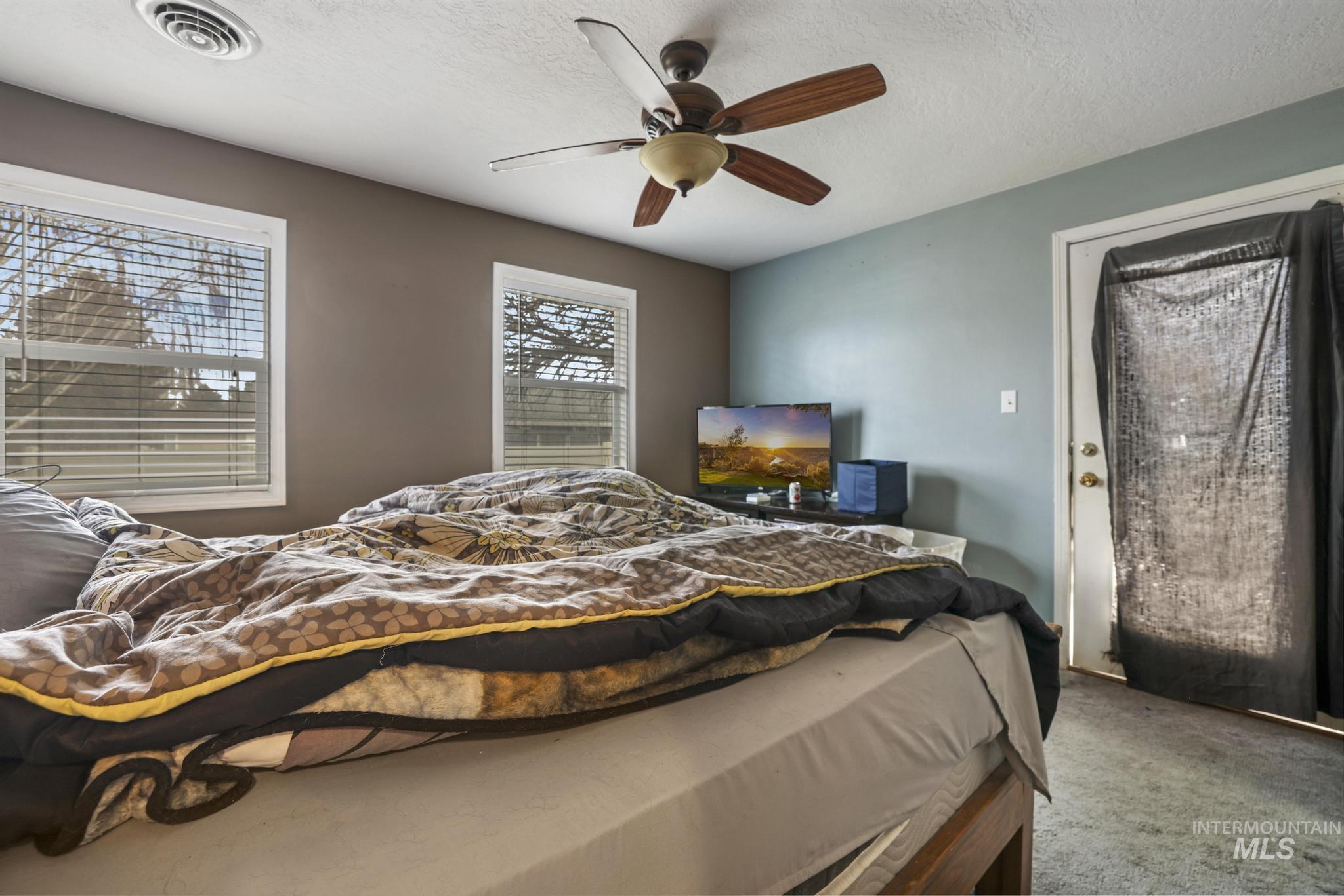 Carpeted bedroom with a textured ceiling and ceiling fan