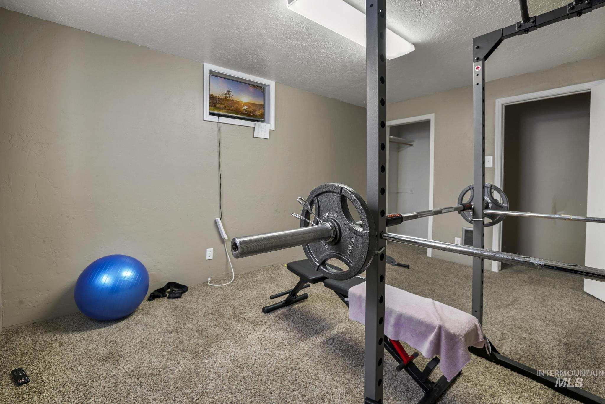 Exercise room with a textured ceiling and carpet