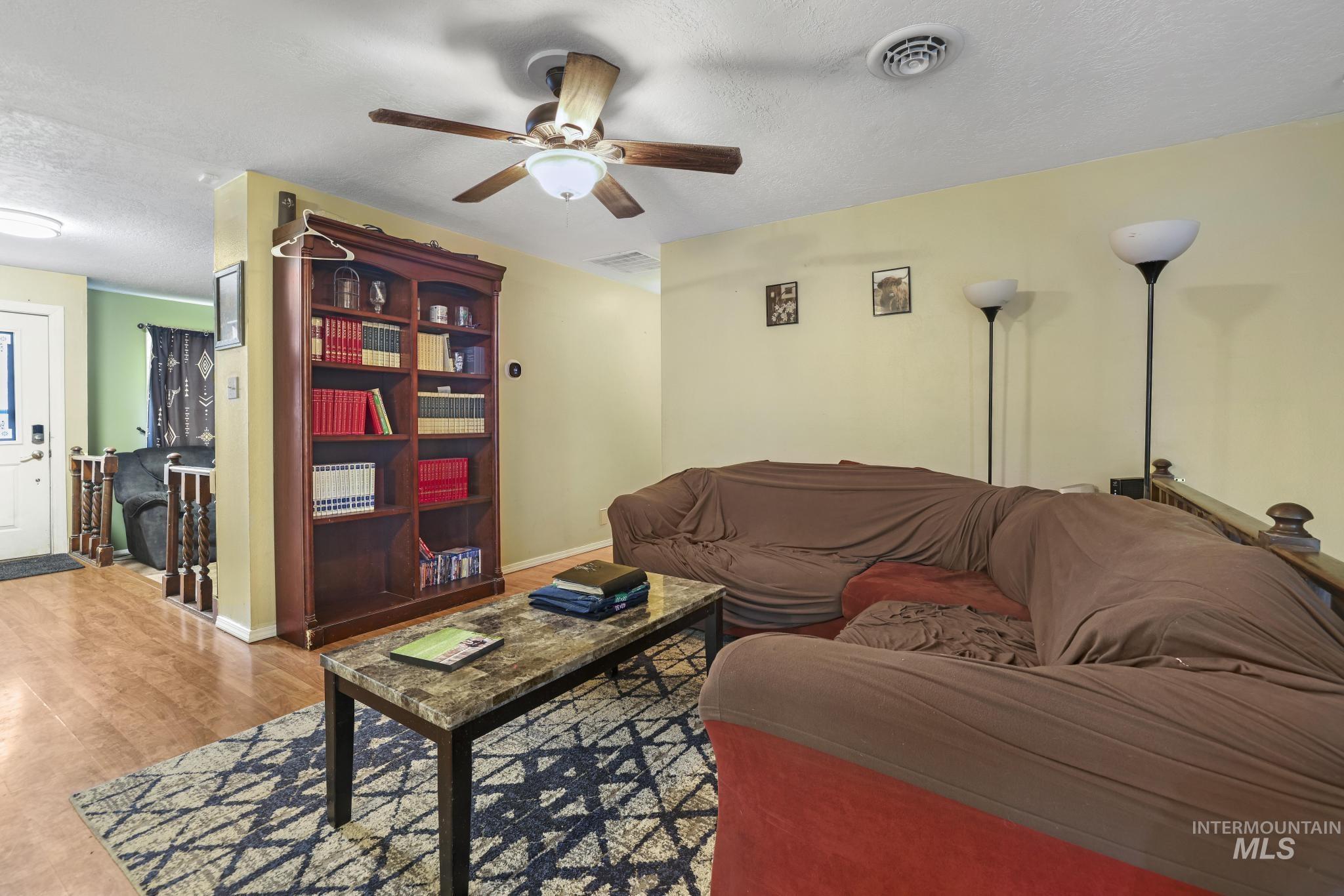 Living area featuring a textured ceiling, wood finished floors, and a ceiling fan