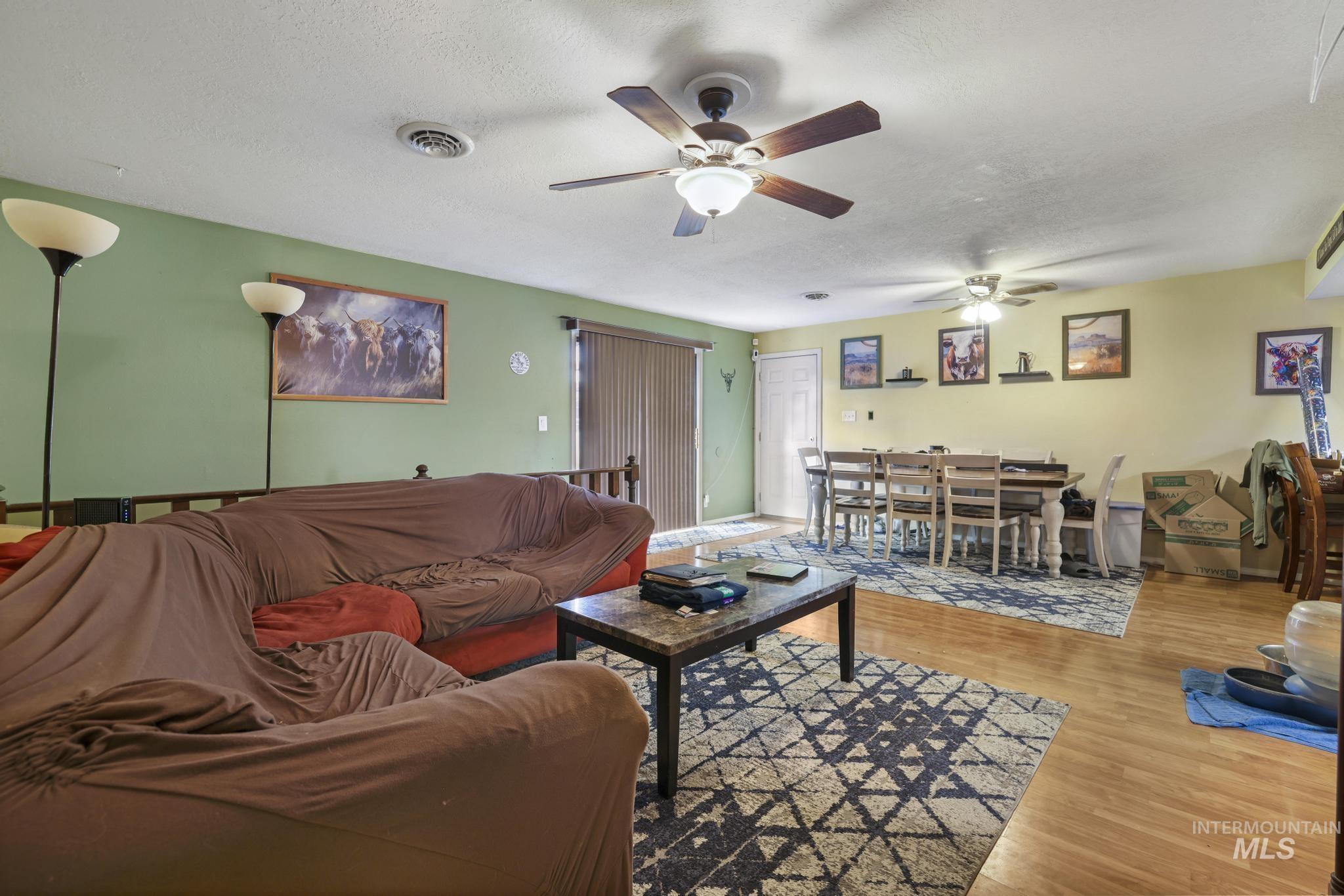 Living room featuring wood finished floors, a textured ceiling, and ceiling fan