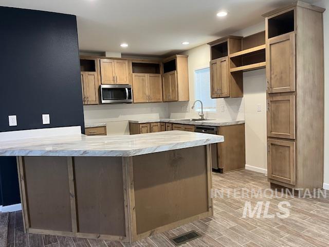 Kitchen with a peninsula, stainless steel appliances, light stone counters, recessed lighting, and wood finish floors