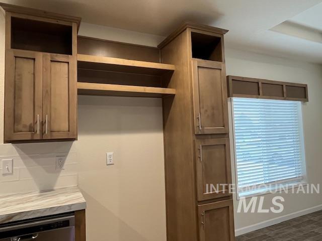 Kitchen with dishwasher, light countertops, brown cabinets, and open shelves