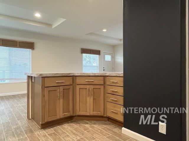 Kitchen featuring brown cabinets, light countertops, wood finish floors, a peninsula, and recessed lighting