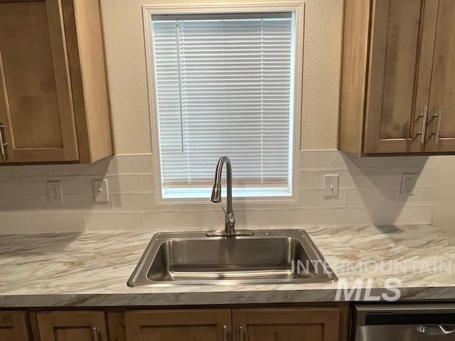 Kitchen featuring light countertops, stainless steel dishwasher, and brown cabinets