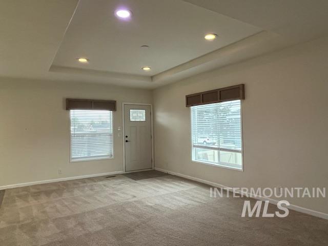 Carpeted entryway with a tray ceiling, healthy amount of natural light, and recessed lighting