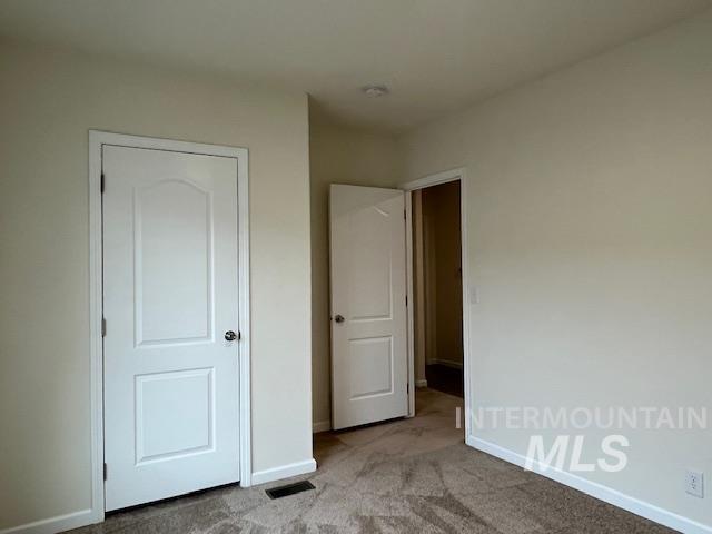 Unfurnished bedroom with light carpet and baseboards