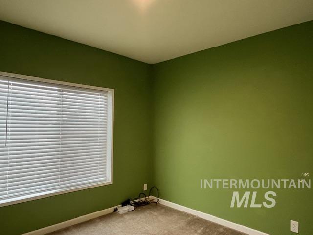 Carpeted spare room featuring baseboards