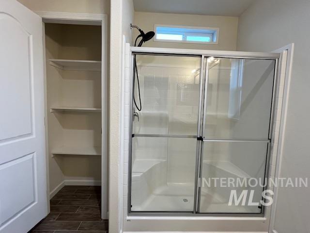 Full bathroom featuring wood finish floors, a shower stall, and a closet