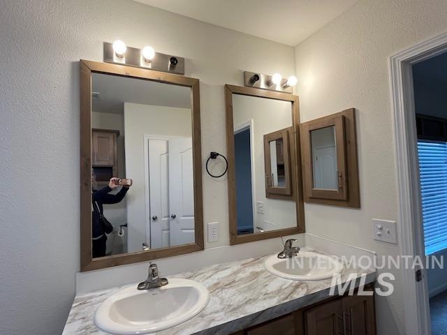 Bathroom featuring double vanity and a textured wall