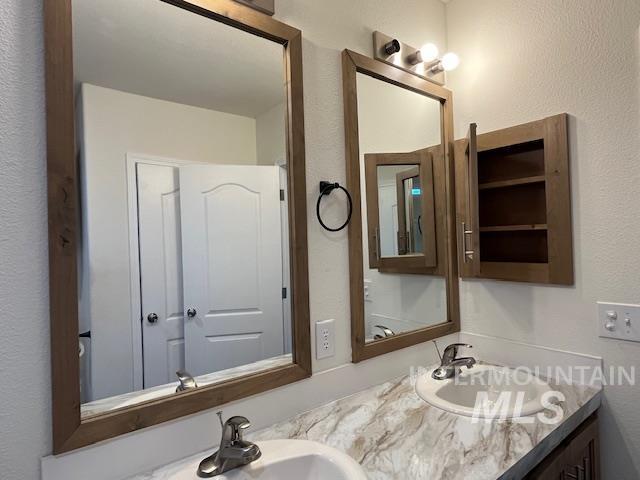 Bathroom featuring a textured wall and double vanity