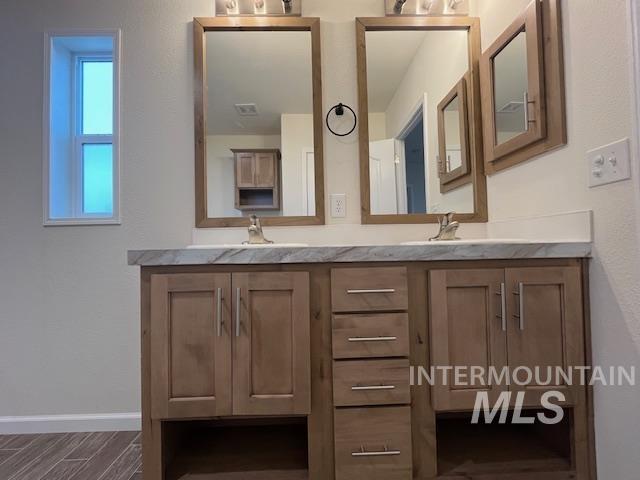 Full bath featuring double vanity and wood finish floors