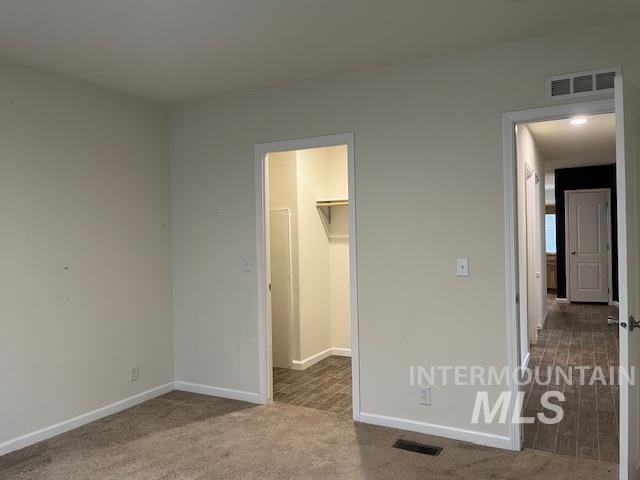 Unfurnished bedroom with a walk in closet and carpet floors