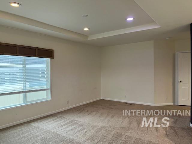 Unfurnished room with recessed lighting, light colored carpet, and a raised ceiling