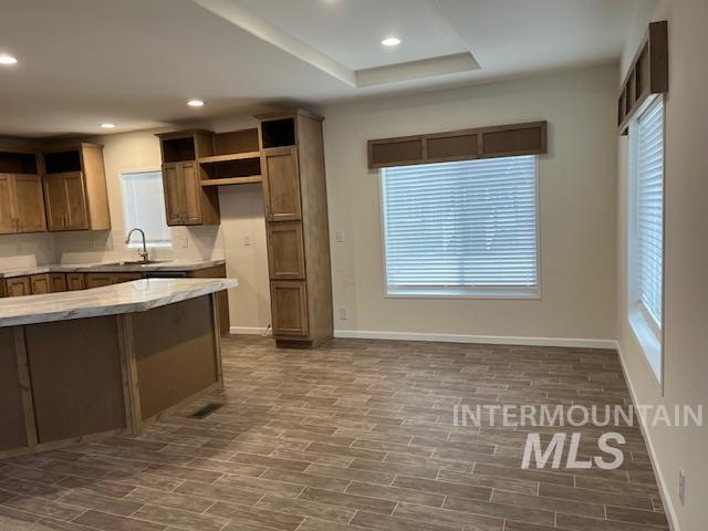 Kitchen featuring brown cabinets, recessed lighting, open shelves, wood tiled floors, and a tray ceiling