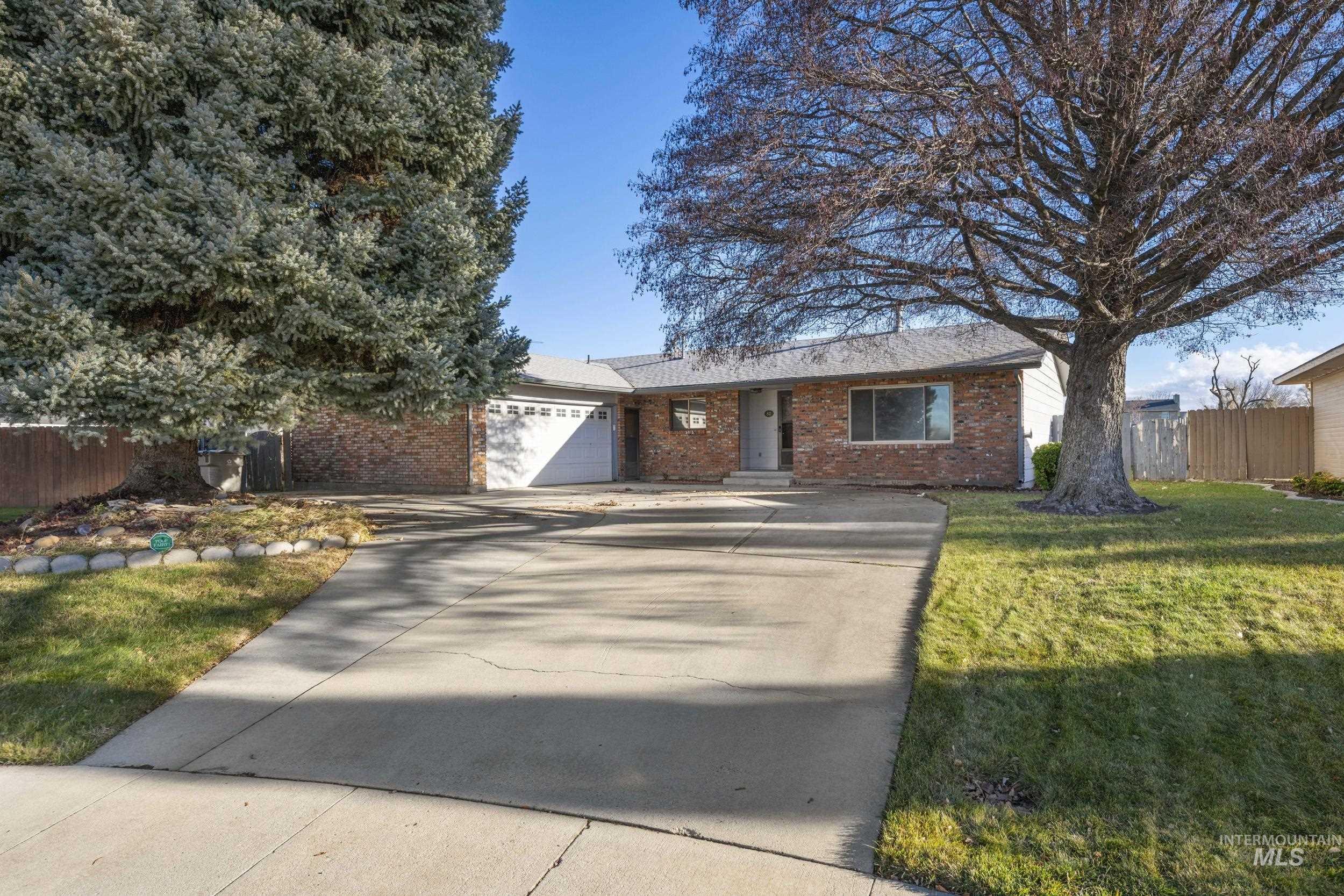 Ranch-style home with concrete driveway, a garage, brick siding, and a shingled roof