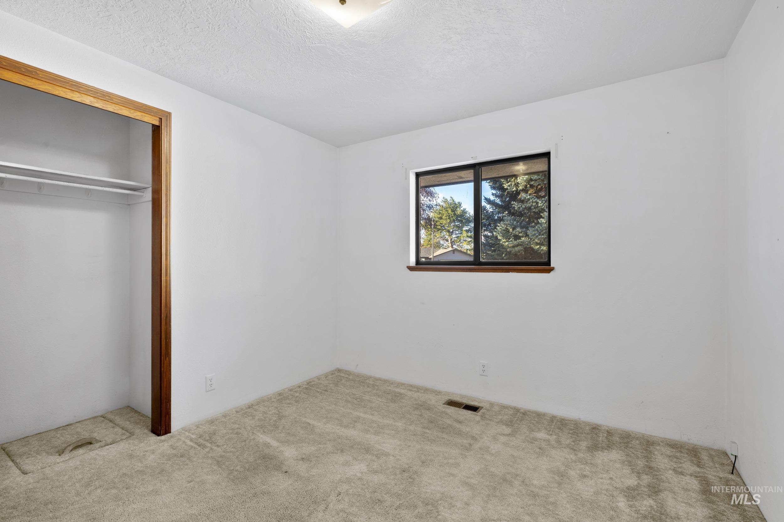 Unfurnished bedroom with a textured ceiling, a closet, and carpet flooring