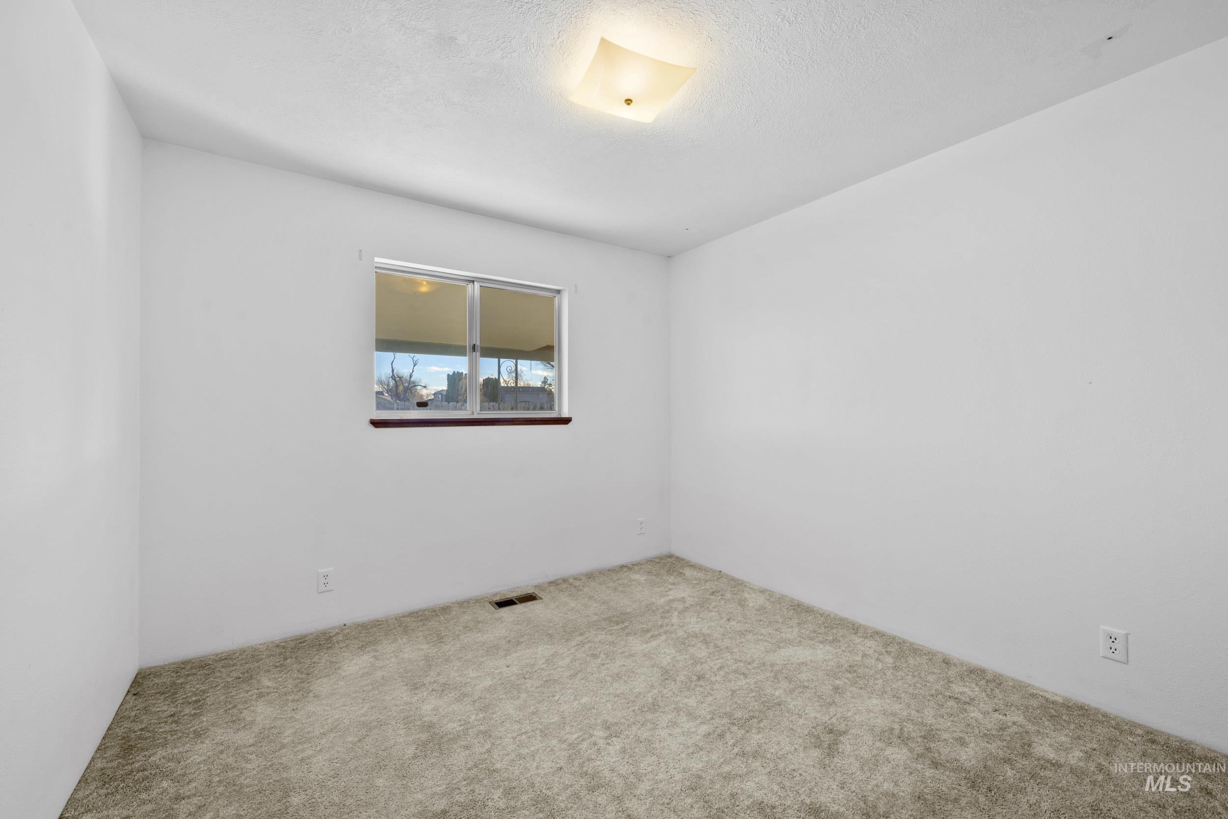 Empty room featuring a textured ceiling and carpet flooring