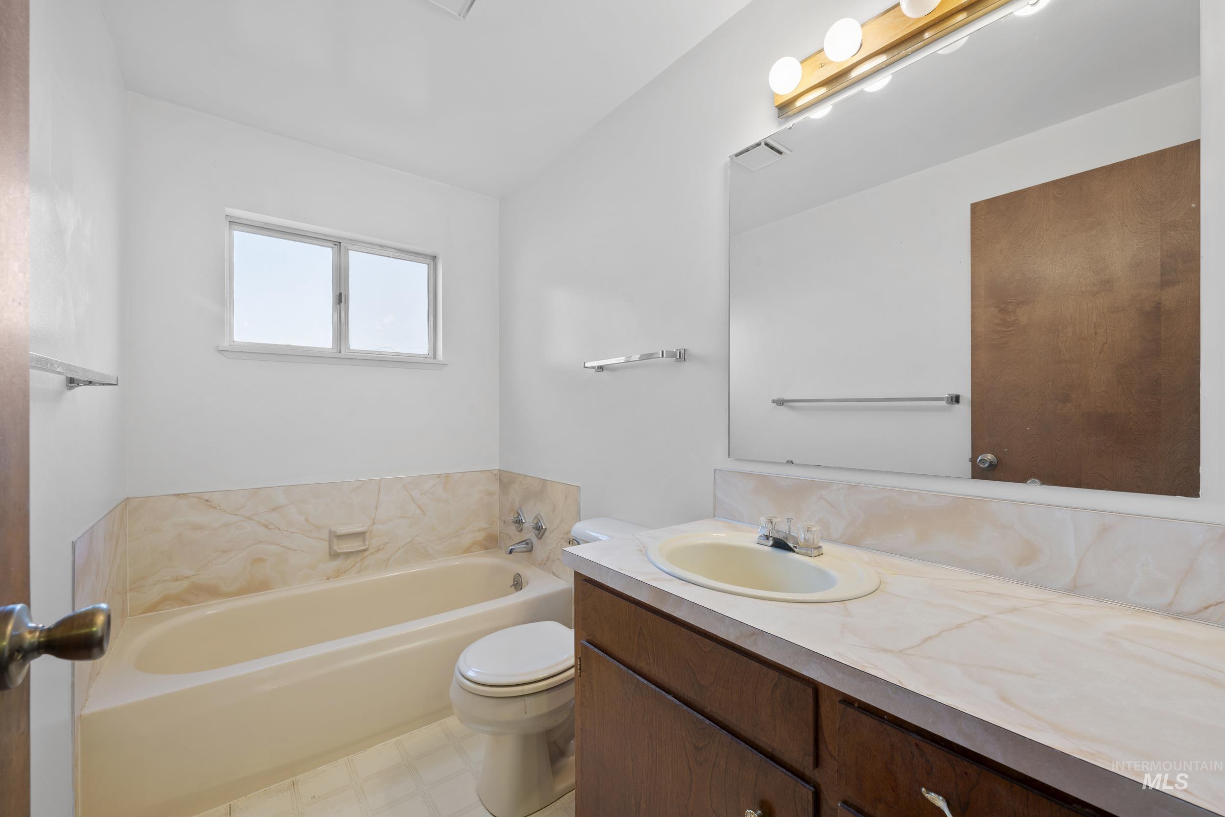 Full bath featuring a bath, vanity, and light floors