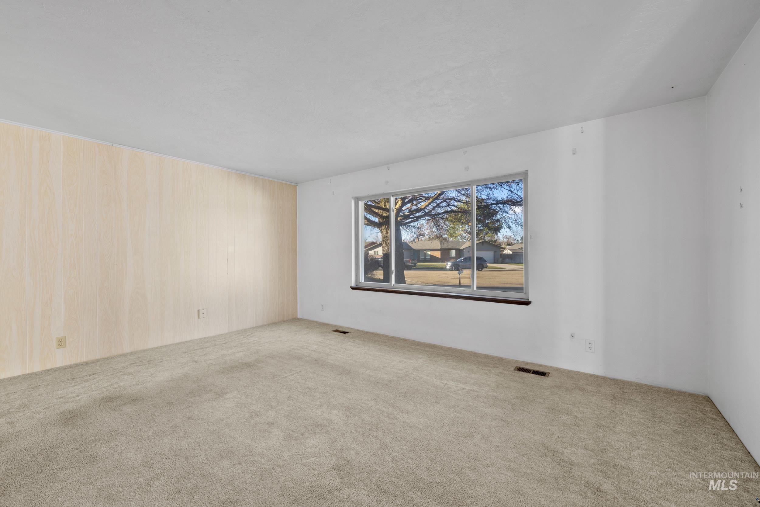 Carpeted spare room with wooden walls