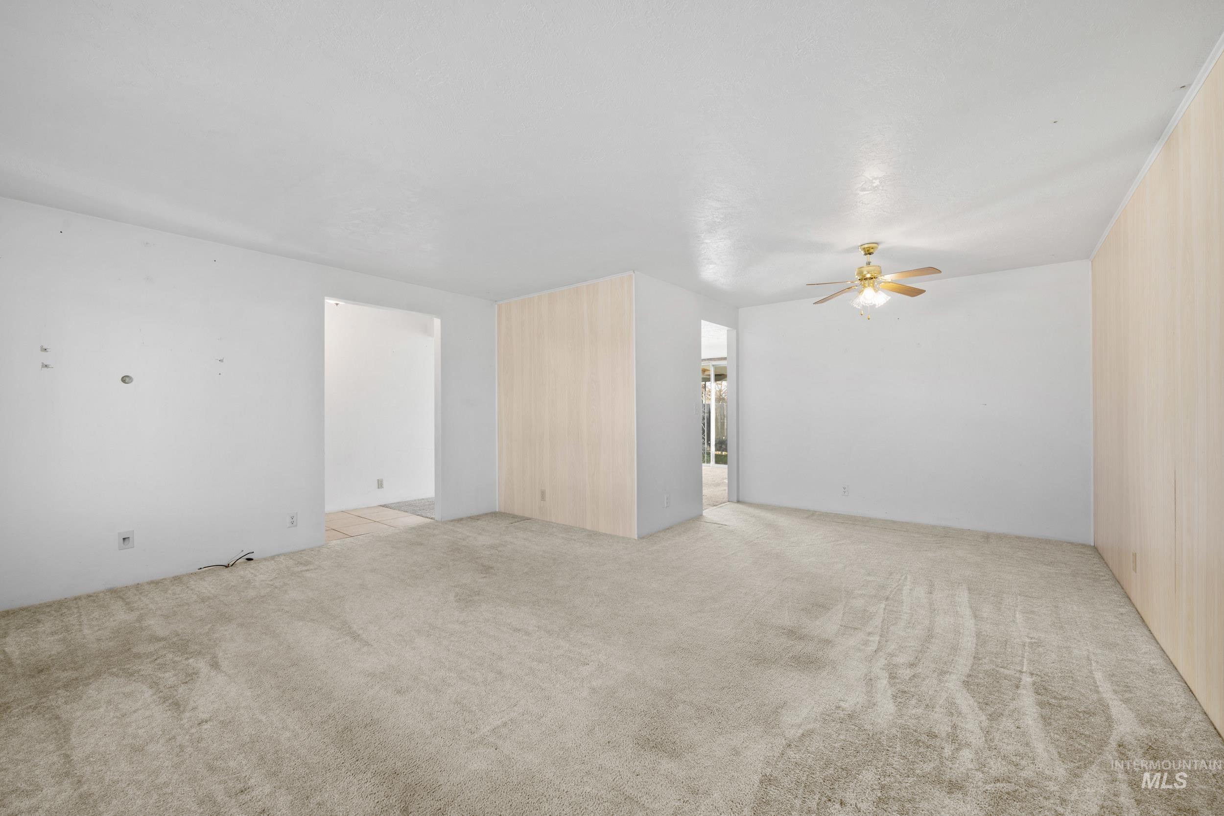 Empty room with light colored carpet and a ceiling fan