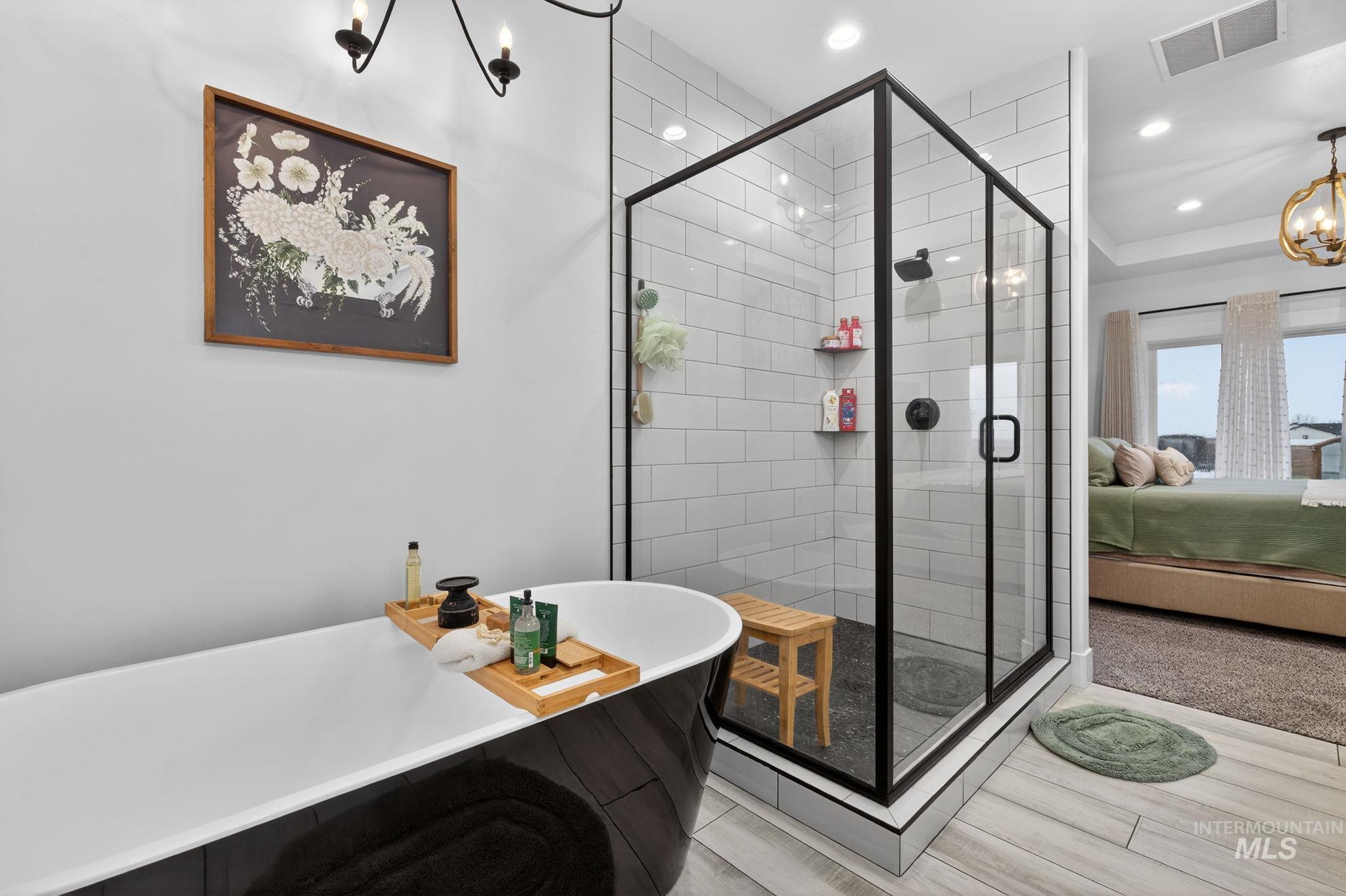 Bathroom with a chandelier, a freestanding tub, ensuite bathroom, recessed lighting, and a shower stall