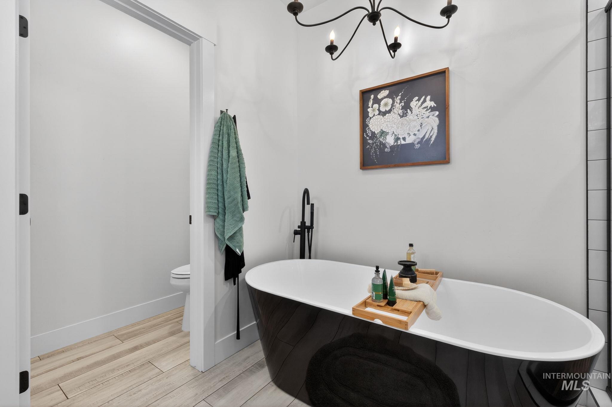 Full bath with a freestanding tub, a chandelier, and wood tiled floors