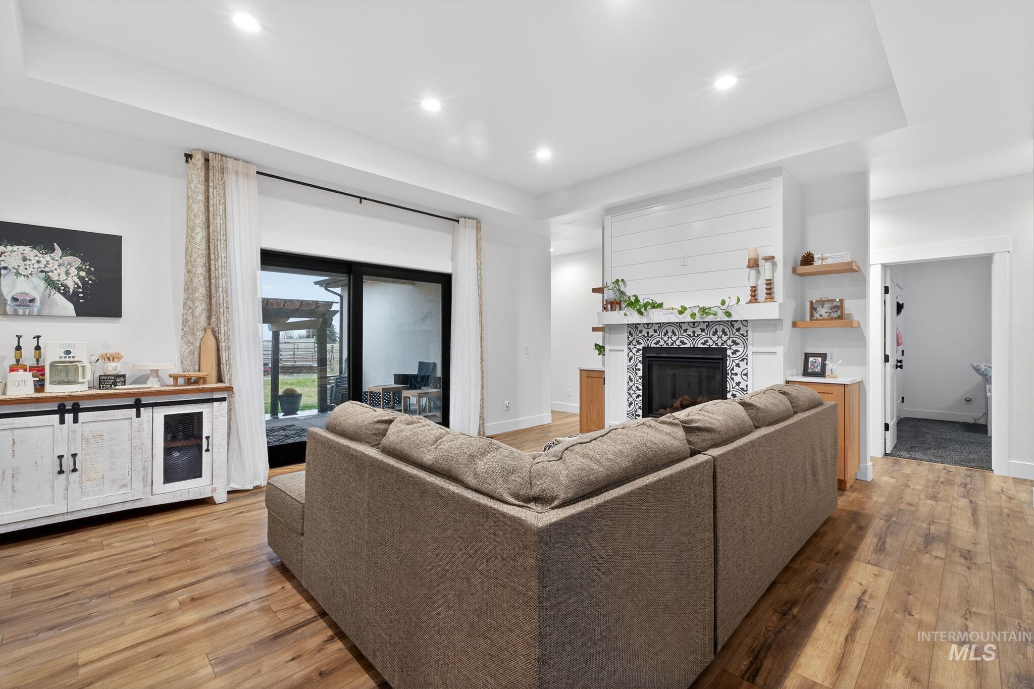 Living room featuring a fireplace, recessed lighting, light wood-type flooring, and a tray ceiling