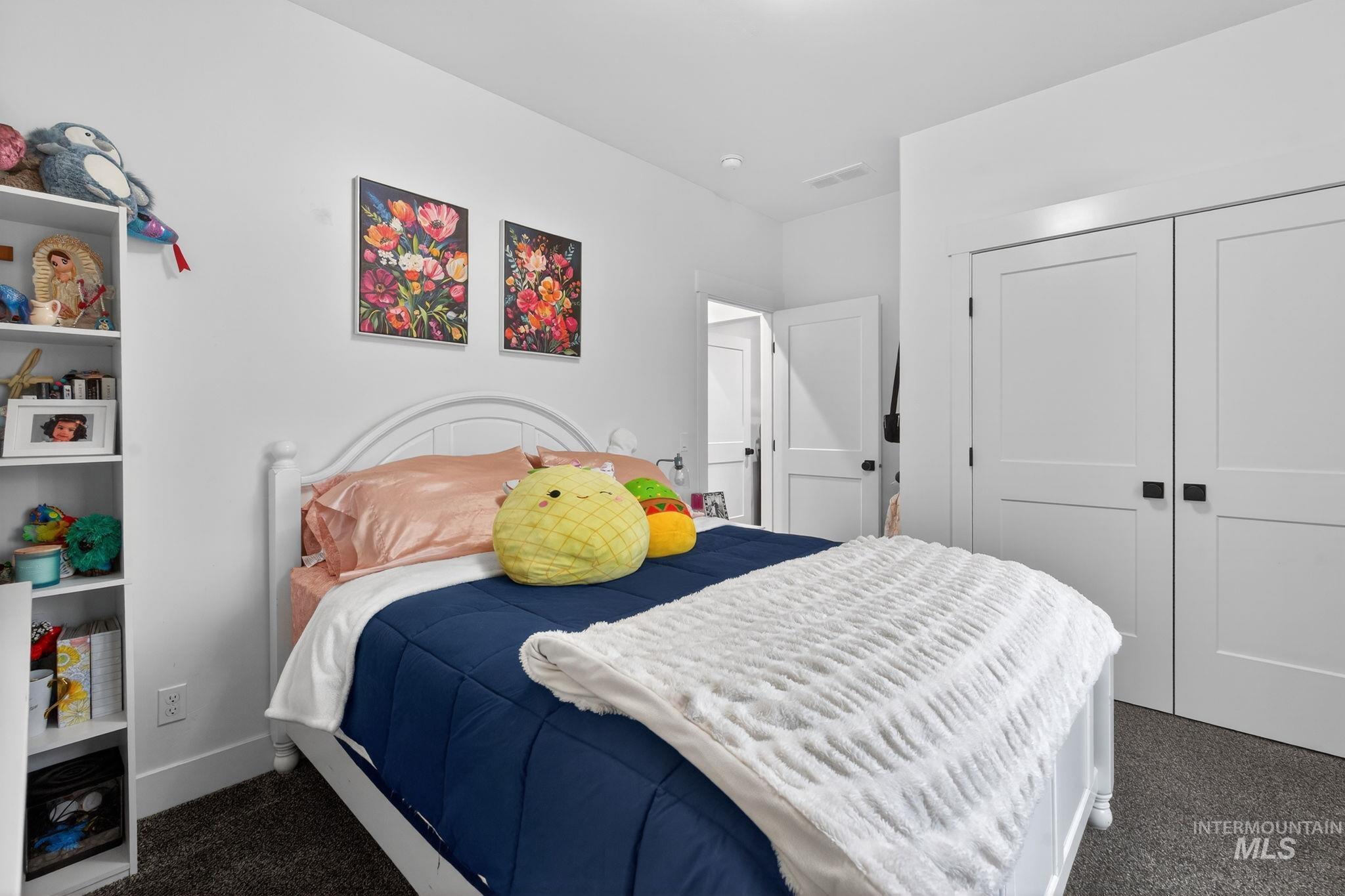 Bedroom with dark colored carpet and a closet