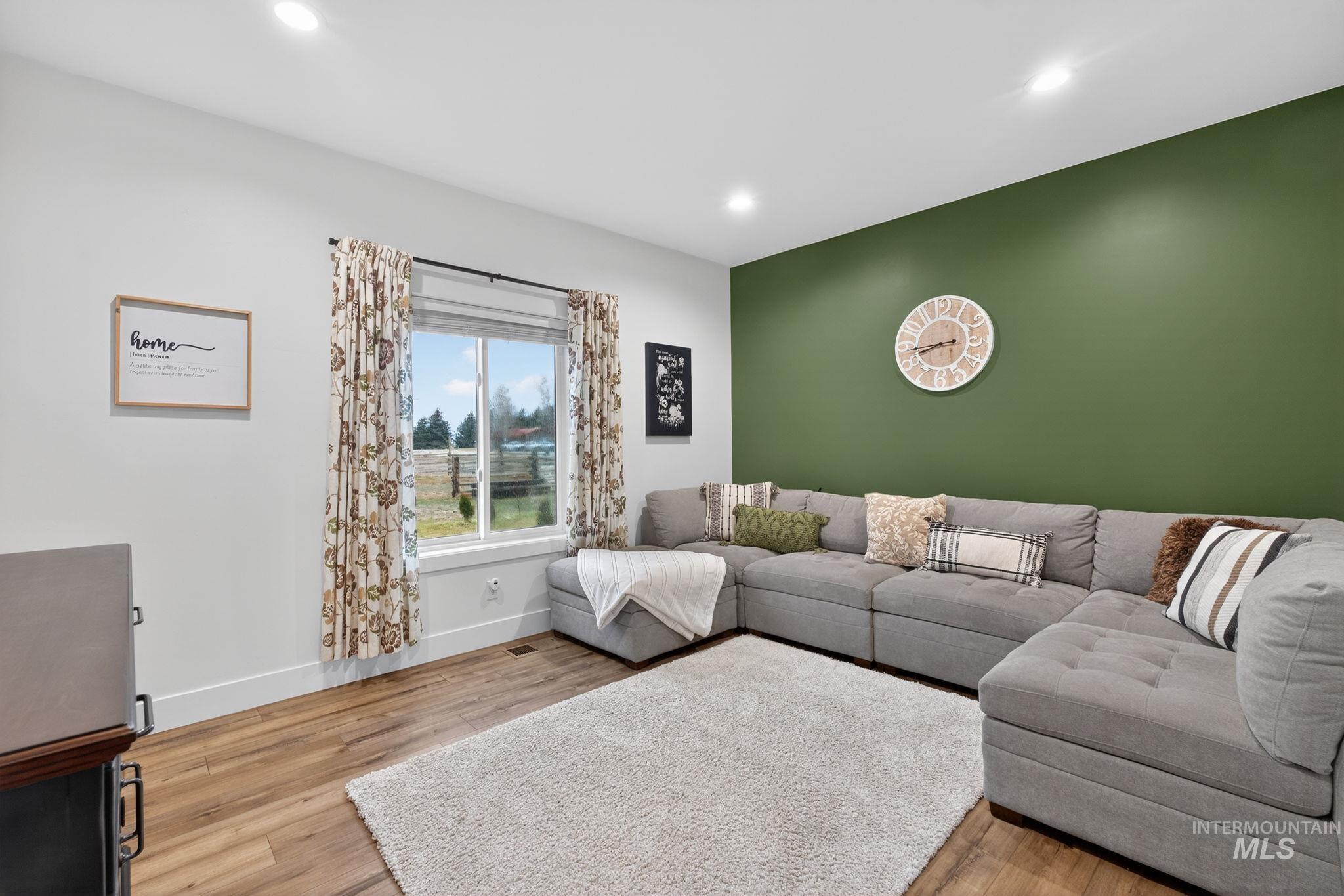 Living room featuring light wood finished floors, an accent wall, and recessed lighting