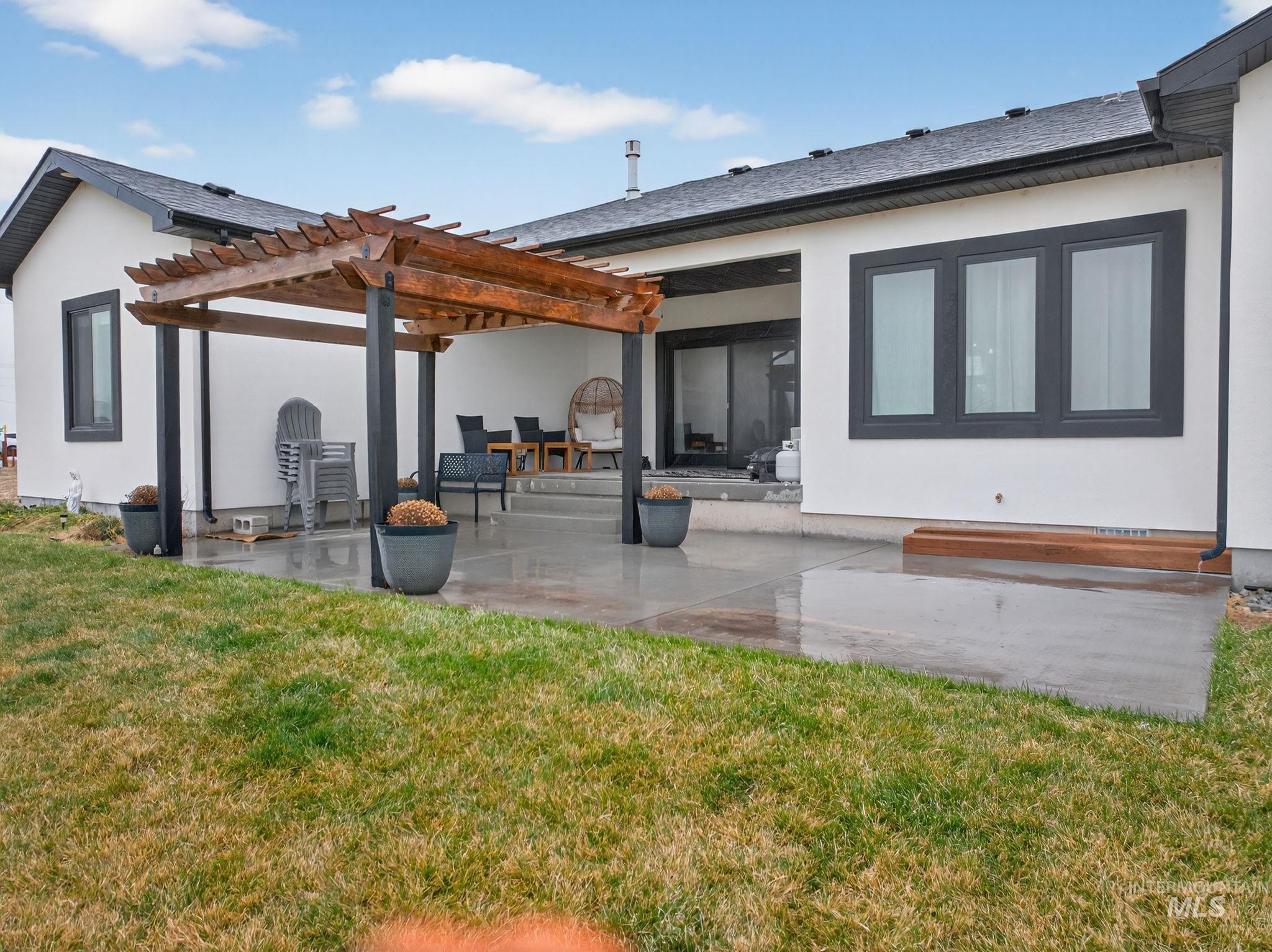 Back of property featuring a patio, a lawn, stucco siding, and a pergola