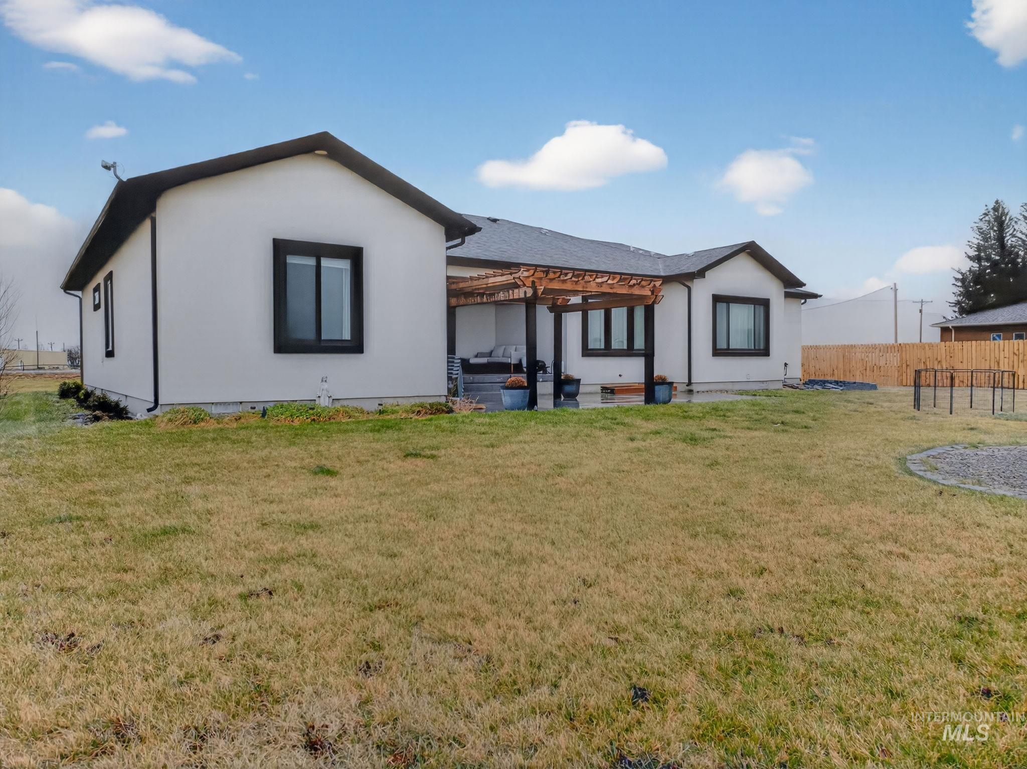 Rear view of property with a pergola, a patio area, and stucco siding