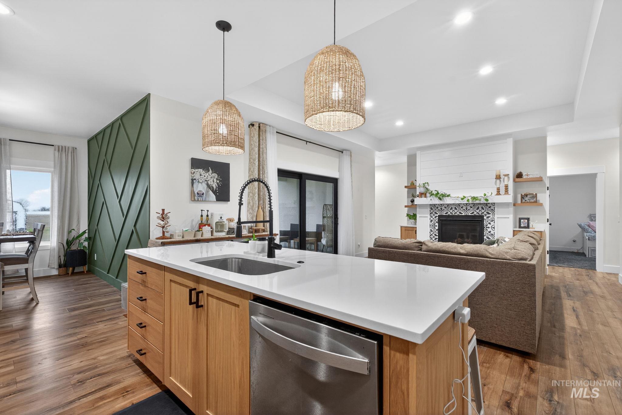 Kitchen with stainless steel dishwasher, dark wood finished floors, pendant lighting, a fireplace, and recessed lighting