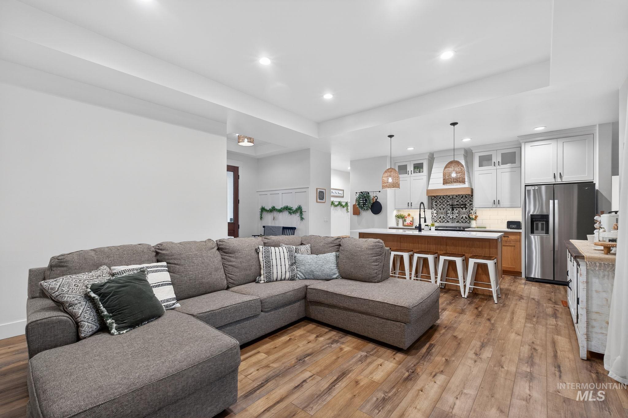 Living room featuring recessed lighting, light wood-type flooring, and a tray ceiling