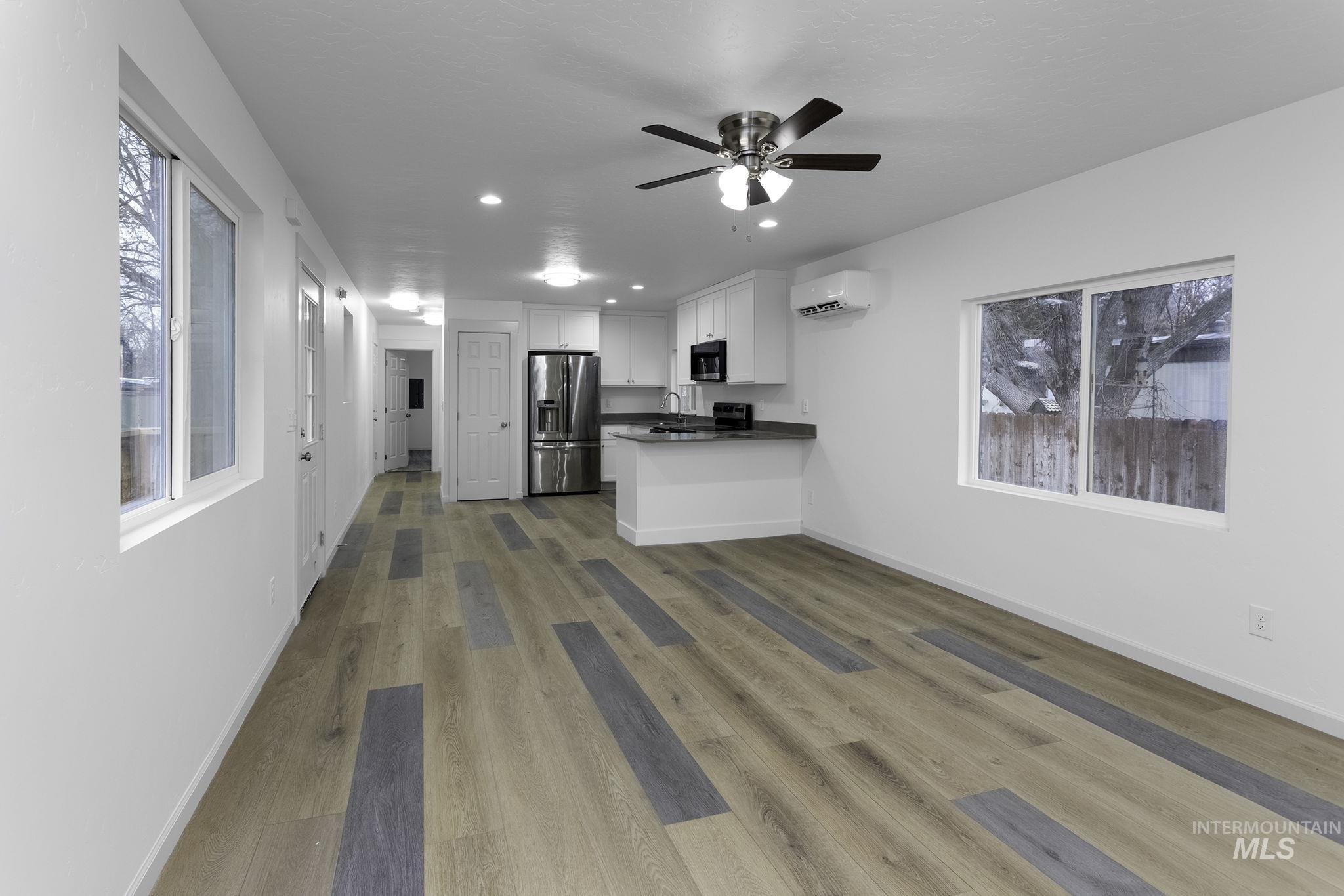 Kitchen featuring white cabinets, healthy amount of natural light, recessed lighting, dark wood-style flooring, and stainless steel fridge