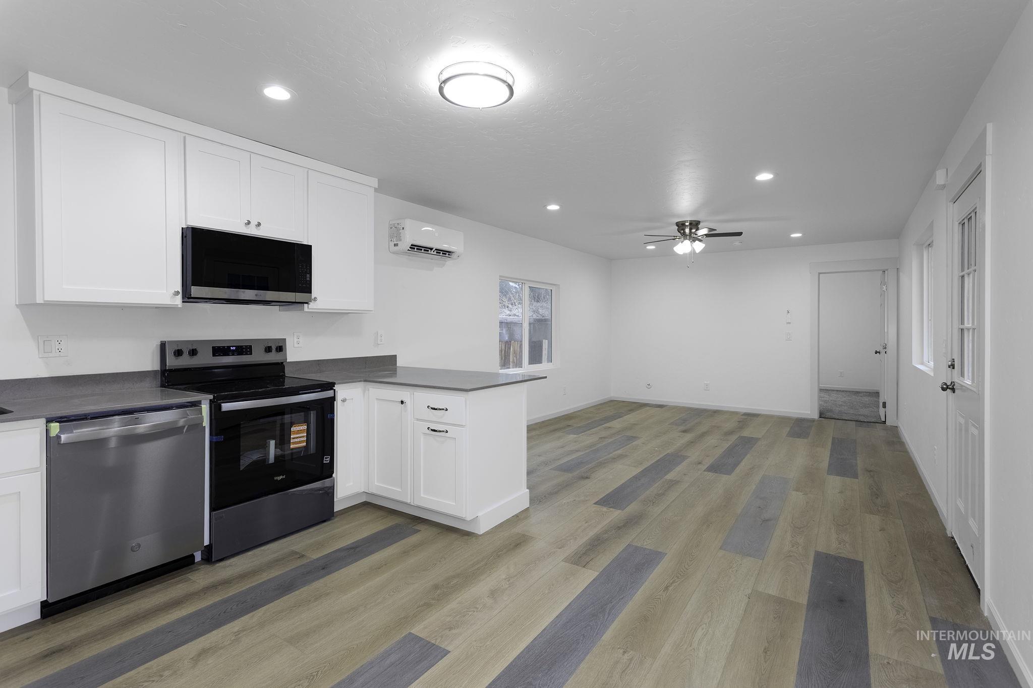 Kitchen with a peninsula, stainless steel appliances, white cabinetry, recessed lighting, and dark countertops