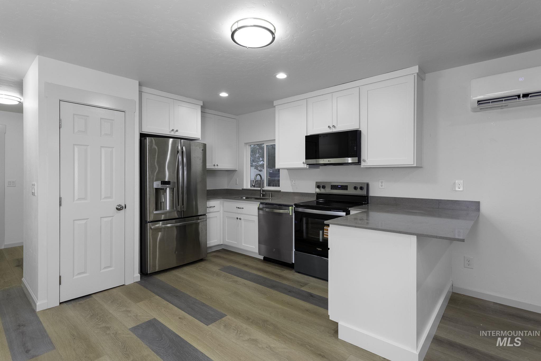 Kitchen featuring stainless steel appliances, white cabinets, a peninsula, dark stone counters, and recessed lighting