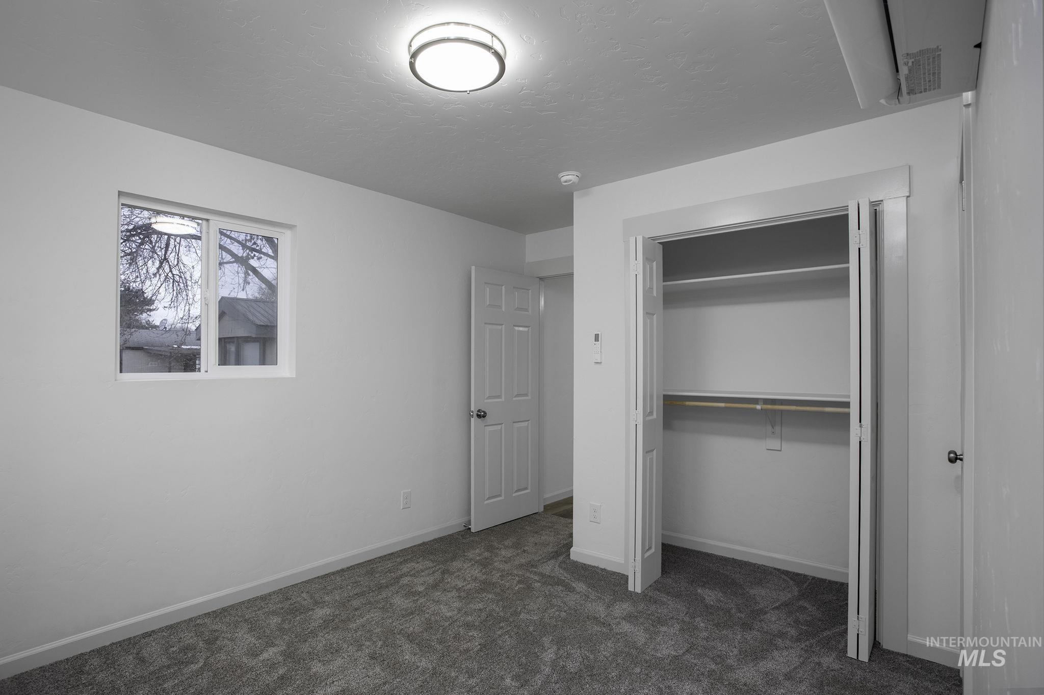 Unfurnished bedroom with dark carpet, a closet, and a textured ceiling