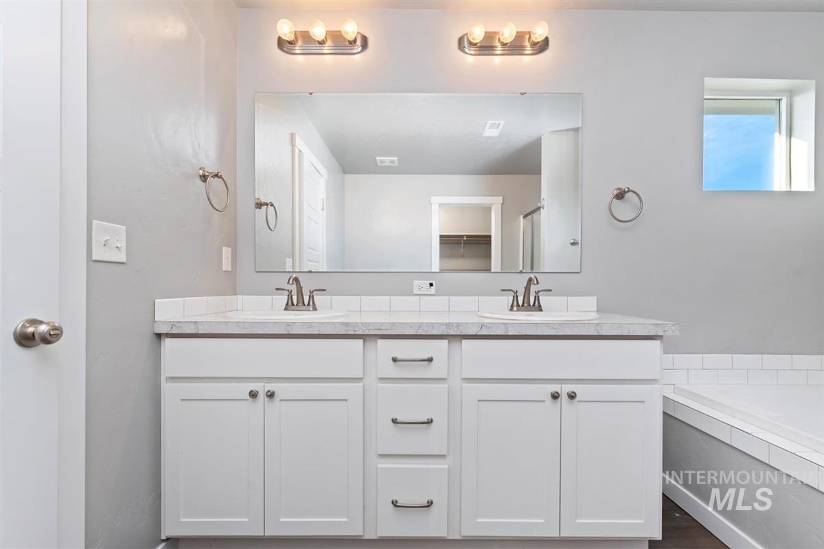 Bathroom with double vanity, a garden tub, and a closet