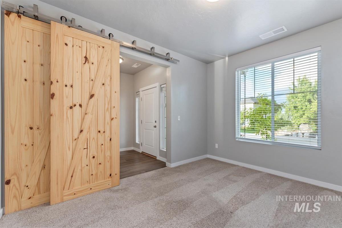 Empty room with light colored carpet and a barn door