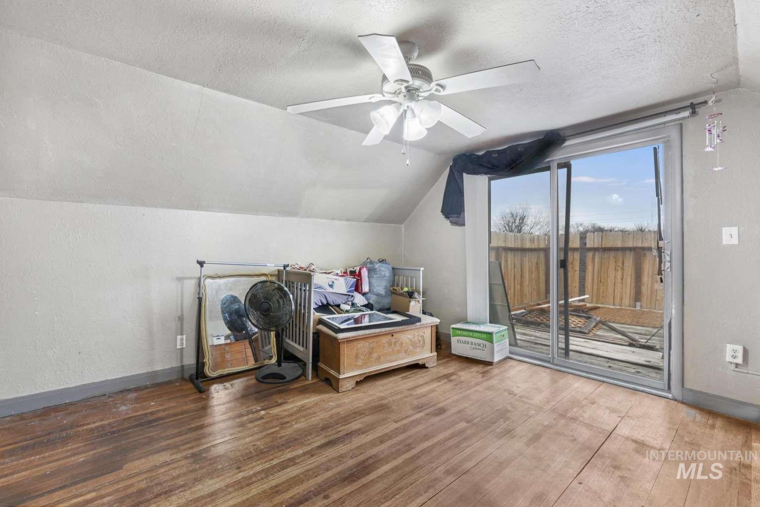 Office featuring lofted ceiling, a textured ceiling, wood finished floors, a ceiling fan, and a textured wall