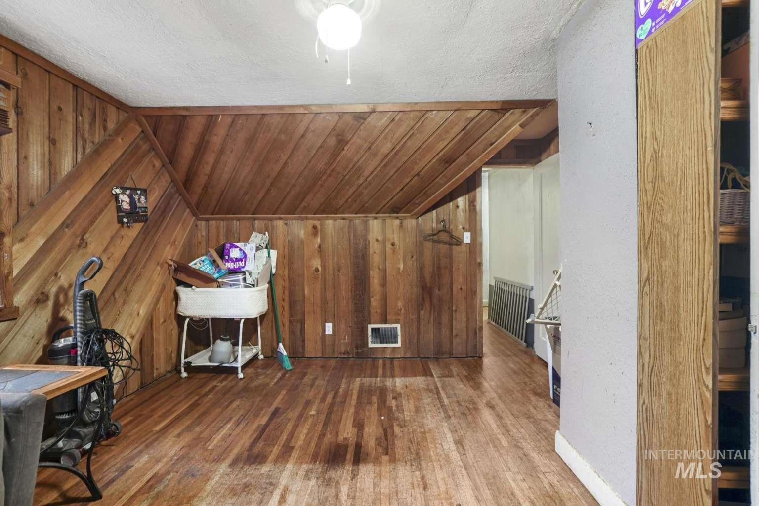 Bonus room with wood-type flooring, radiator heating unit, lofted ceiling, wooden walls, and a relaxing sauna