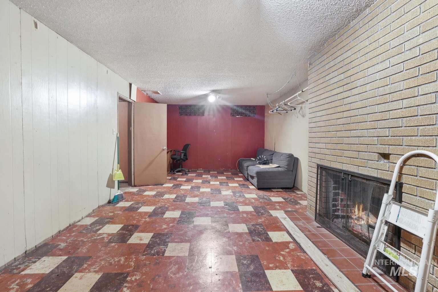 Finished below grade area with wooden walls, tile patterned floors, a fireplace, and a textured ceiling