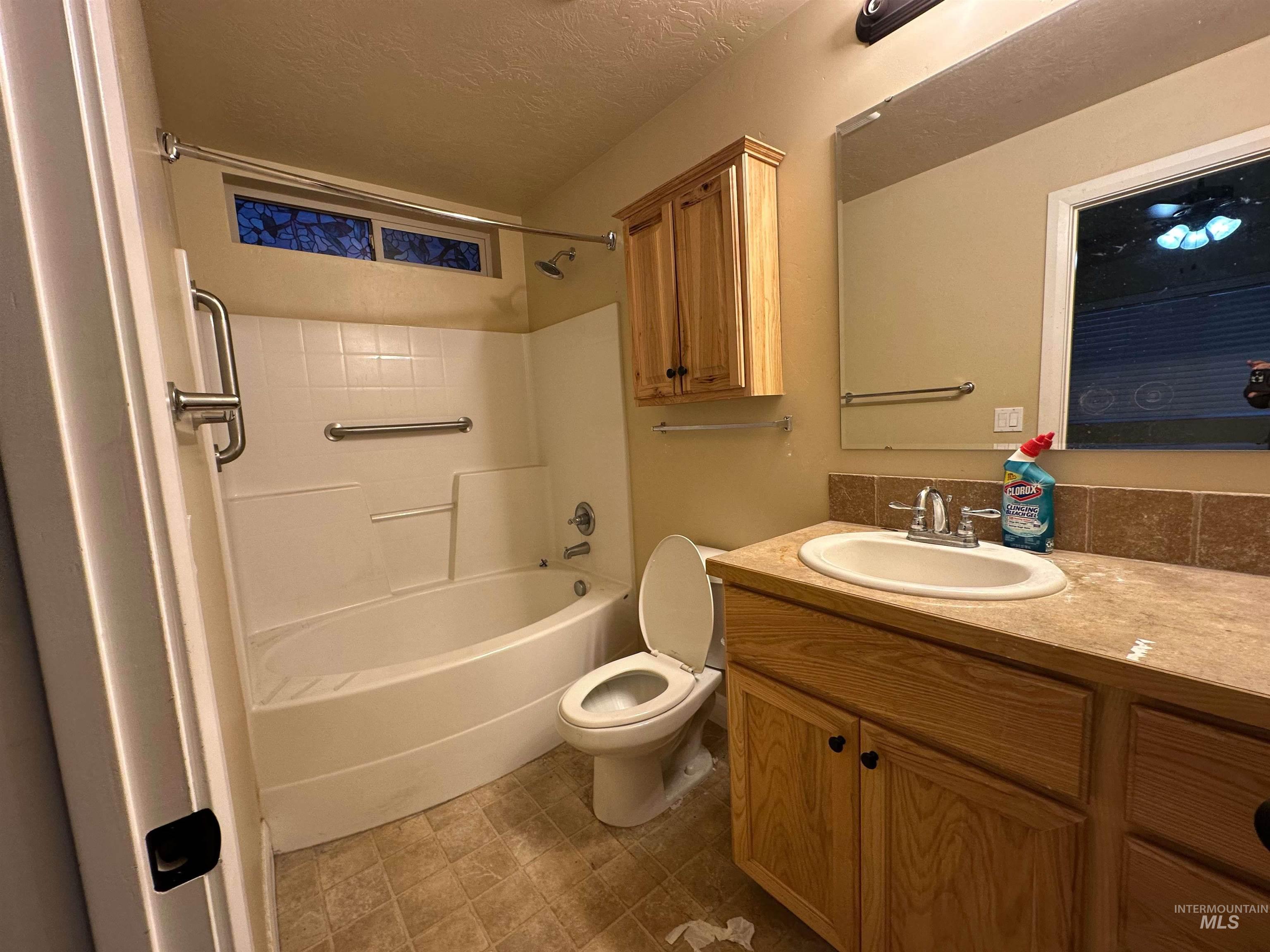 Bathroom with vanity, tub / shower combination, and a textured ceiling