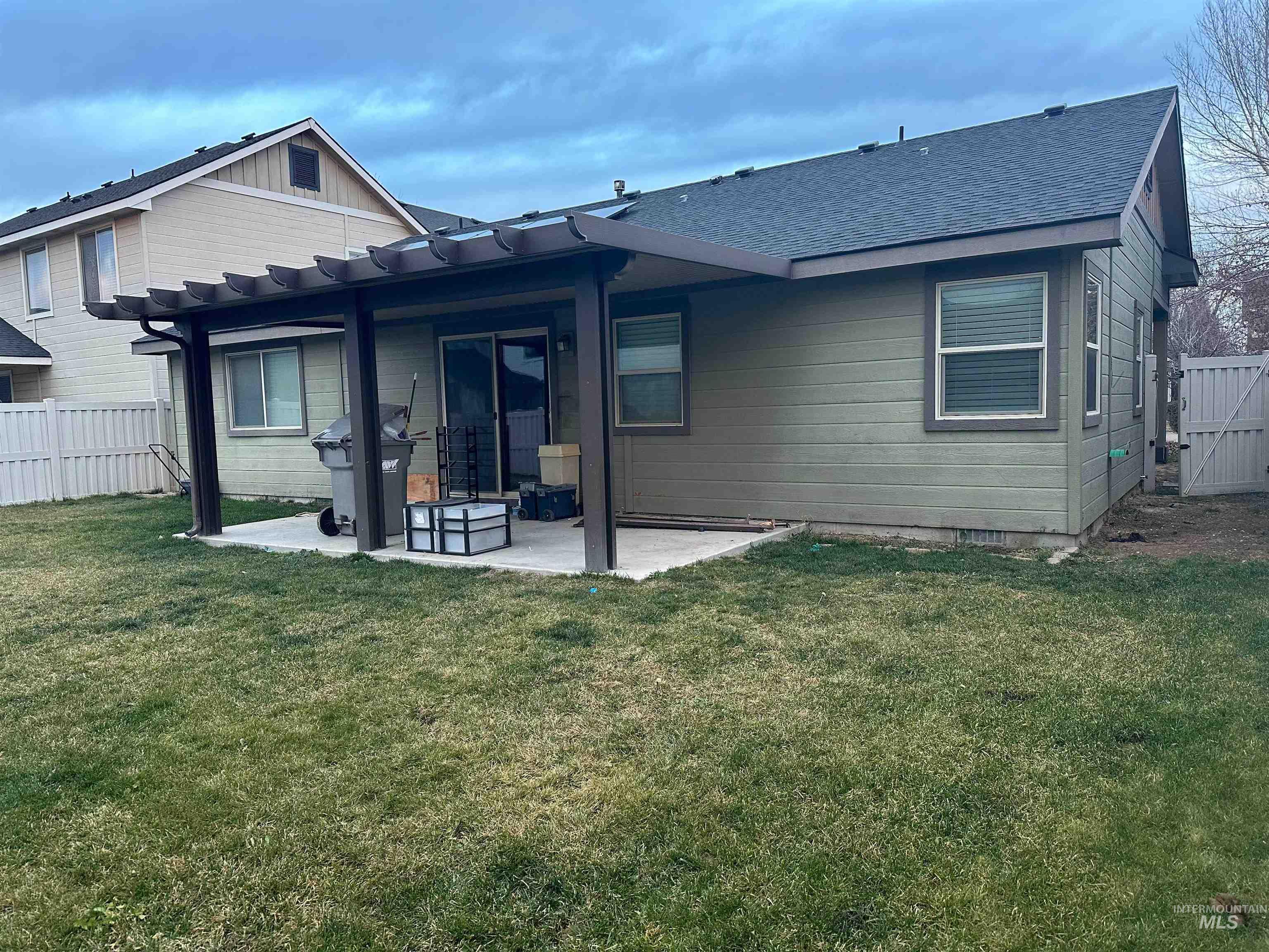 Rear view of property with a patio, a shingled roof, and a gate