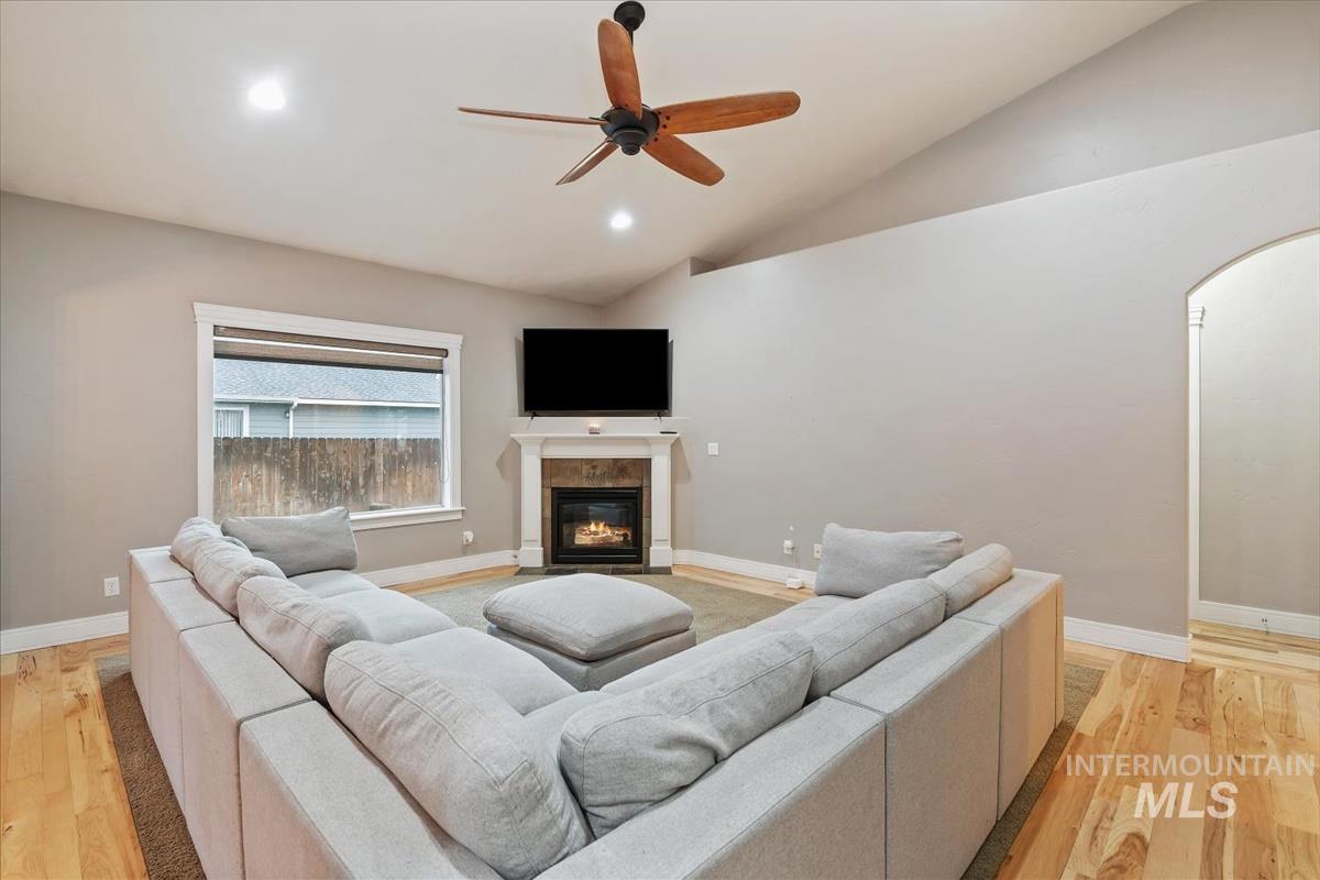 Living area with vaulted ceiling, light wood-type flooring, a fireplace, a ceiling fan, and recessed lighting