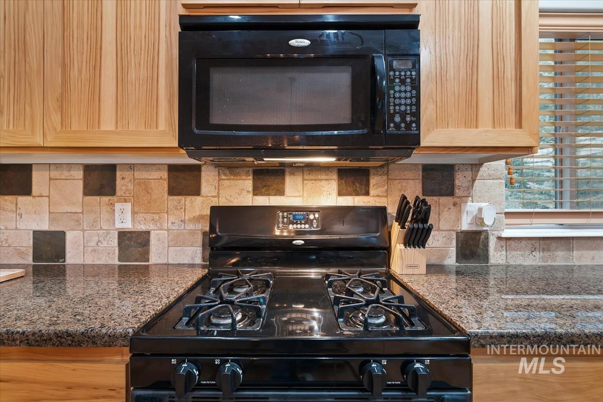 Kitchen featuring black appliances, dark stone countertops, and decorative backsplash